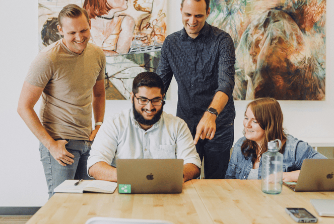 four people working on a laptop