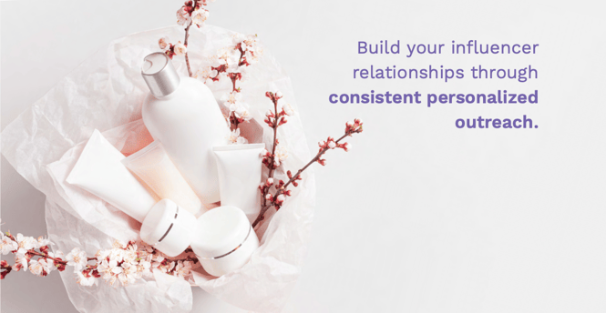 A photo of a package of products, pink and white flowers, and white tissue paper with the sentence "Build your influencer relationships through consistent personalized outreach" superimposed in purple text.