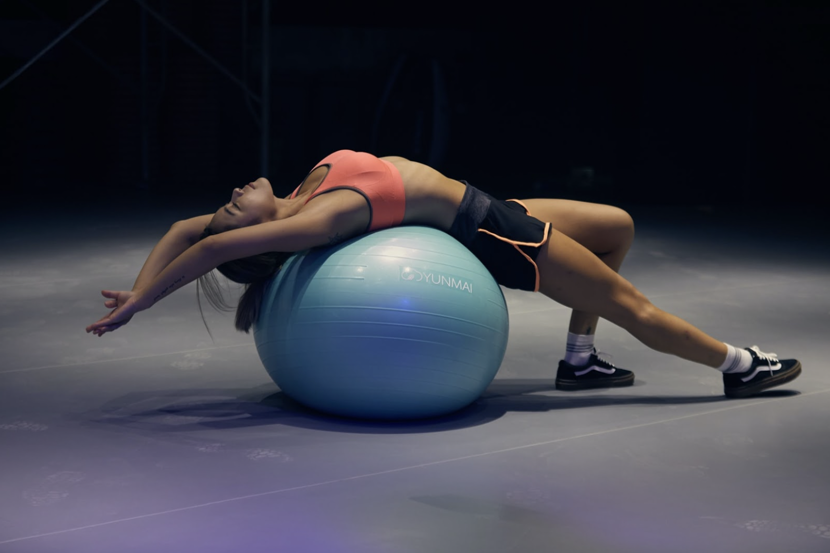 A fitness influencer in apparel from an activewear brand on an exercise ball. 