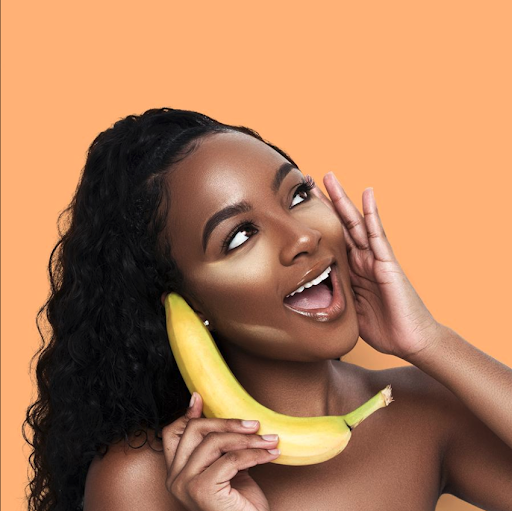 A model wearing Beauty Bakerie’s Flour Setting Powder and holding a banana to her ear like a telephone.