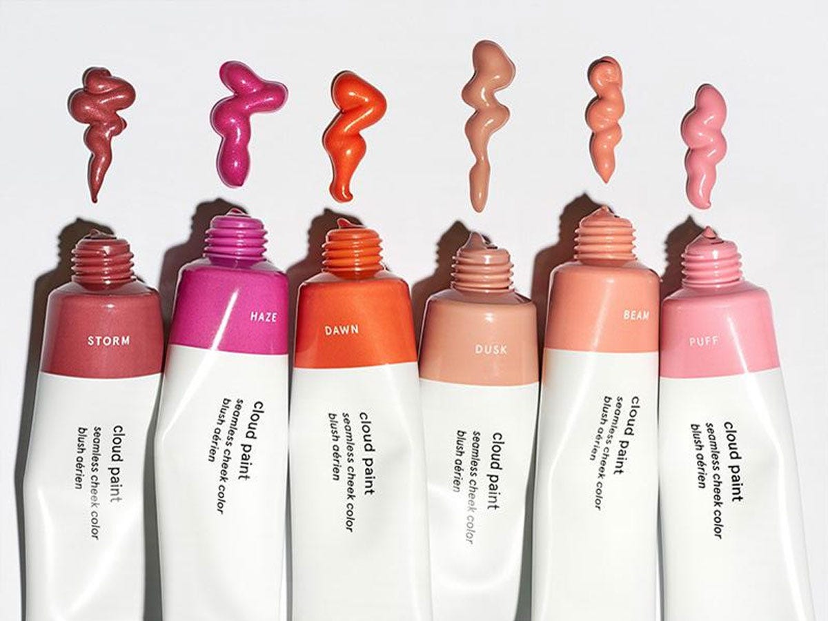 Assorted shades of Glossier’s Cloud Paint liquid blush against a white background. 