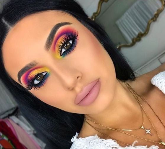 An influencer shows off a colorful cut-crease in her bedroom. 