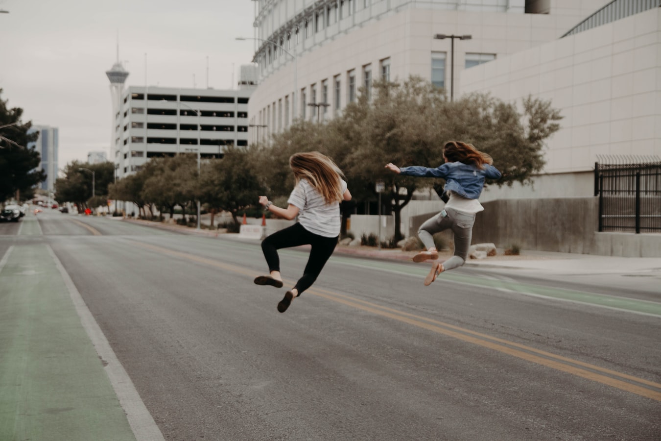 Two influencers jumping side by side in a city street.