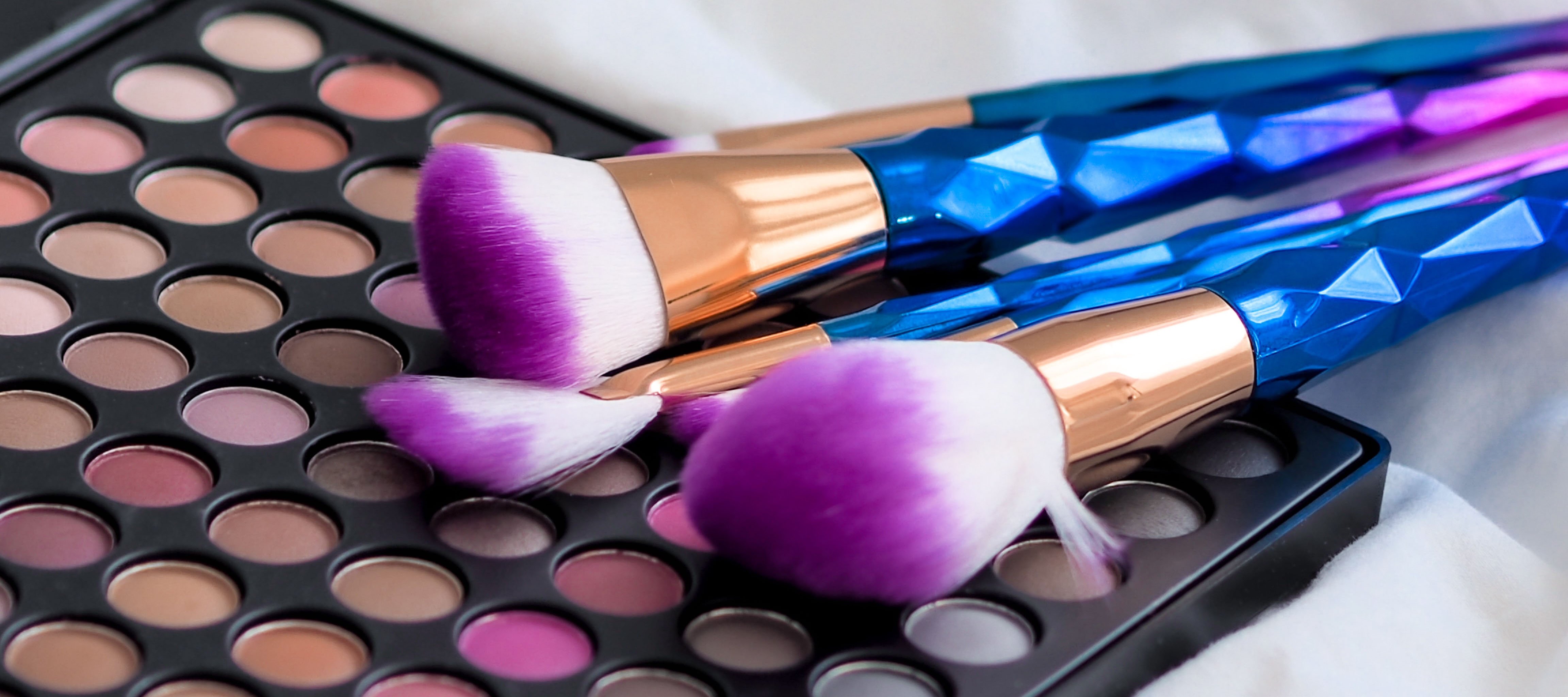 Cosmetic brushes on a colorful makeup palette.