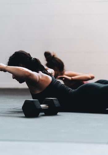 Two women doing pilates in a boutique fitness studio, by Logan Weaver.