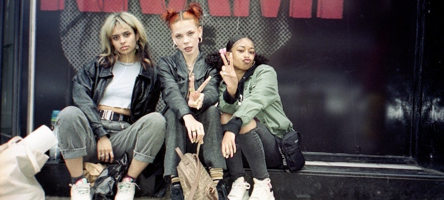 Three fashion influencers seated outside an event venue, by Matt Moloney.