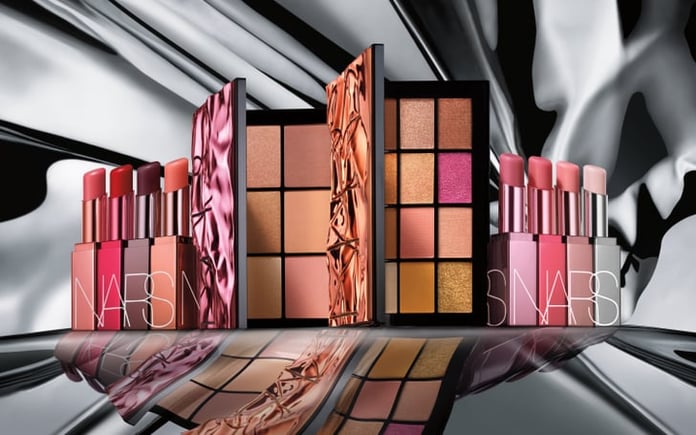 NARS’ Afterglow collection of eye, lip, and complexion products arranged in front of a silver background. 