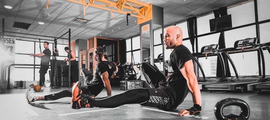 A group of men stretching in an OrangeTheory class.