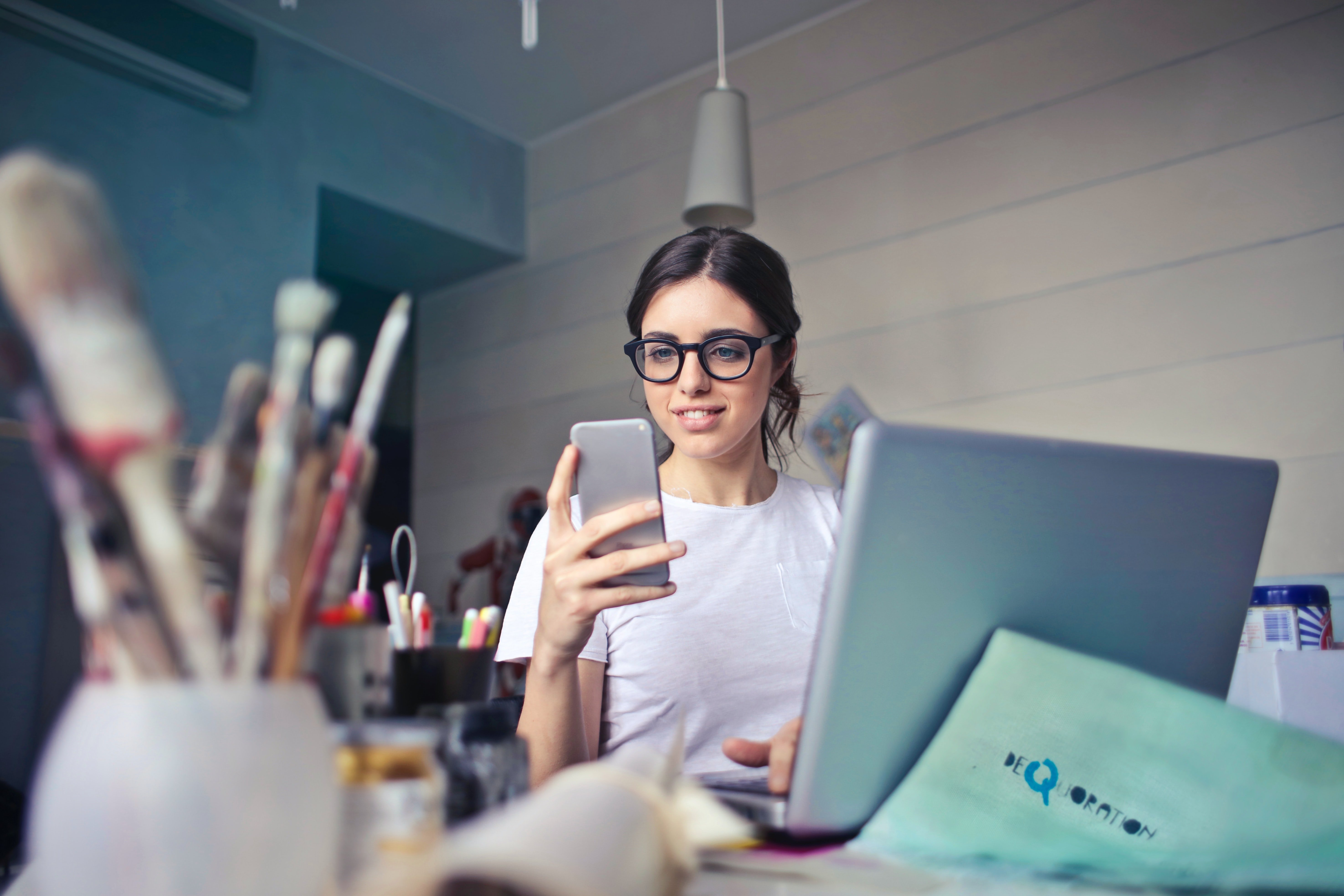 A woman wearing glasses glances at her phone.