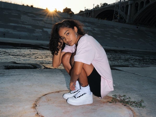 A Gen Z influencer in white sneakers posing at sunset, by Mike Von.