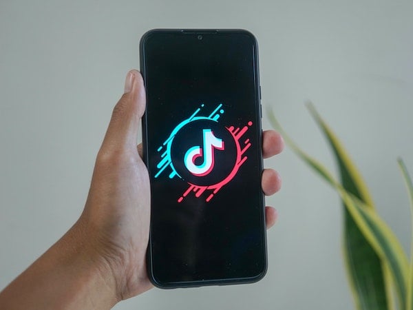 A close-up of a smartphone displaying the TikTok app in a person's hand, by Mourizal Zativa via Unsplash.