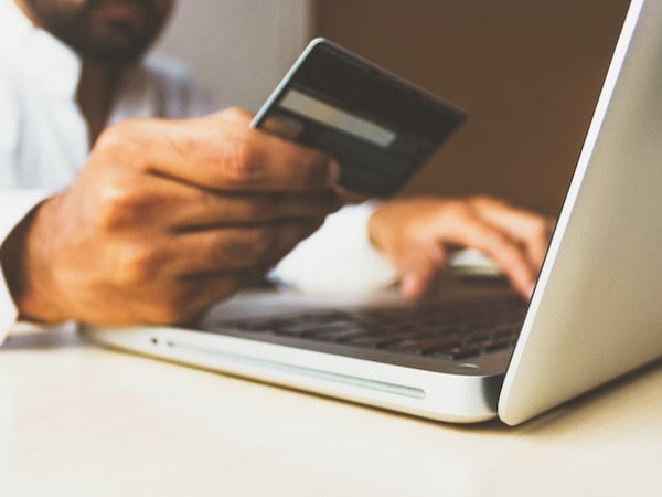 A man with a credit card online shopping, by Rupixen via Unsplash.