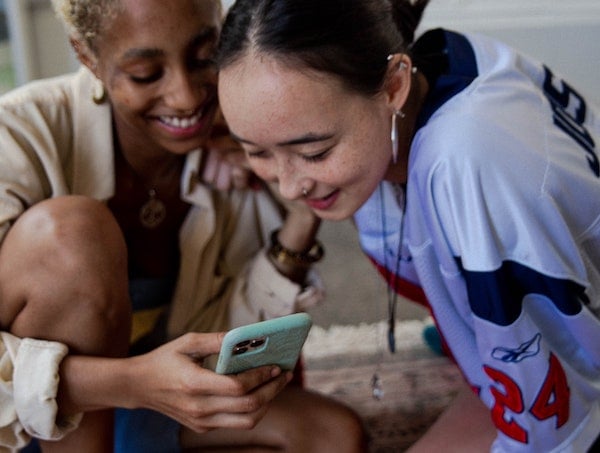 Two Gen Z women viewing TikTok influencer content on a smartphone, by Shingi Rice via Unsplash.