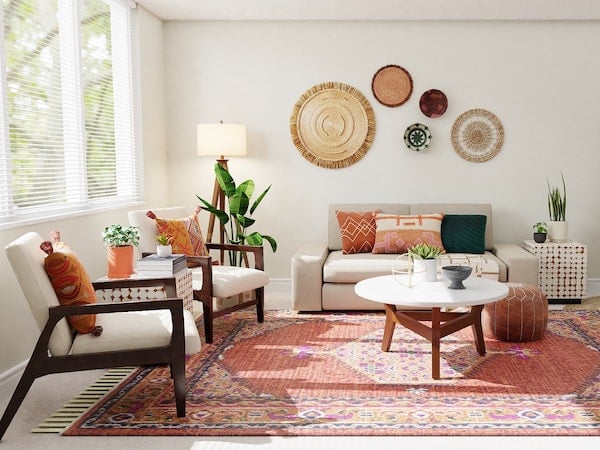 A boho living room with an oriental rug, chairs, a couch, and circular wall hangings, by Spacejoy via Unsplash.
