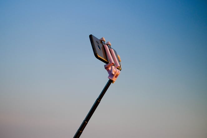 A selfie stick is pictured holding an iPhone. 