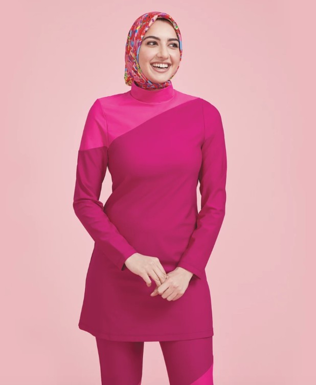 A woman wearing a hijab models Summersalt’s full-coverage swim tunic. 