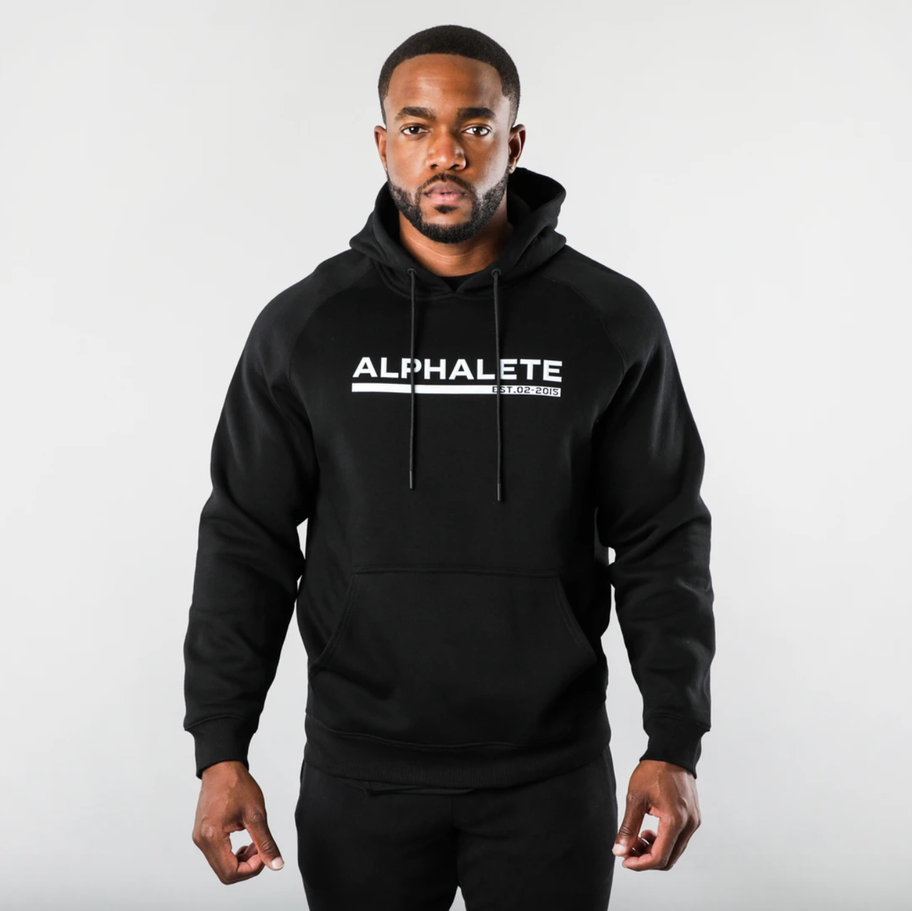 A male model poses in an Alphalete-branded hoodie.