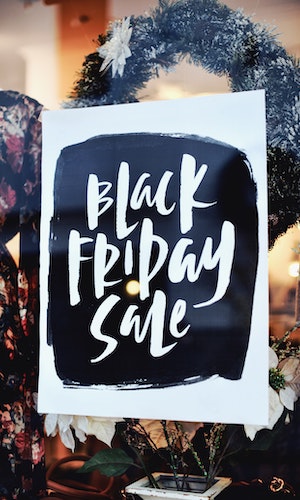 A sign for a Black Friday sale in front of a Christmas wreath, by Tim Mossholder.