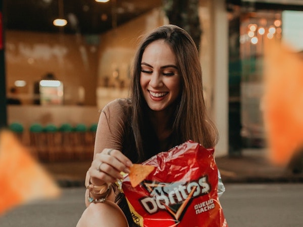 A Gen Z influencer eating a bag of Doritos, by Allef Vinicius via Unsplash.