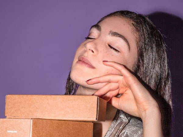 A TikTok creator posing with boxes from a product send, by Curology via Unsplash.