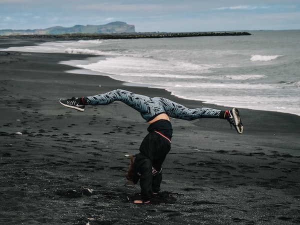 A woman in leggings, a TikTok influencer marketing trend, doing a cartwheel on a beach, by Kalea Morgan via Unsplash. 