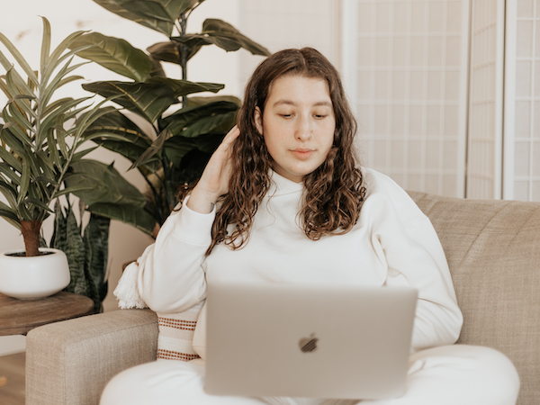 a TikTok creator on a laptop on a couch in front of plants, by Madrona Rose via Unsplash