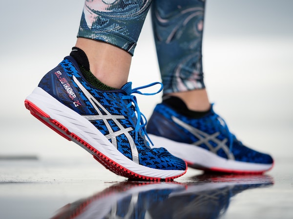 A close-up of blue Asics running shoes on the feet of a fitness TikTok creator, by Malik Skydsgaard via Unsplash.