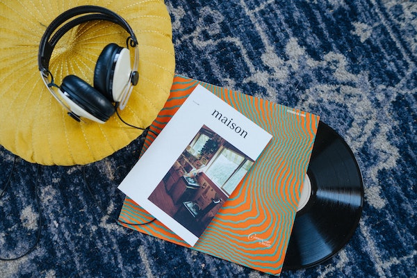 A hip magazine on top of a record next to a pair of headphones, by NMG Network via Unsplash.