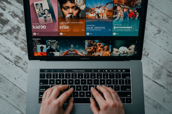 The hands of a person on a laptop open to Hulu, by Tech Daily via Unsplash.